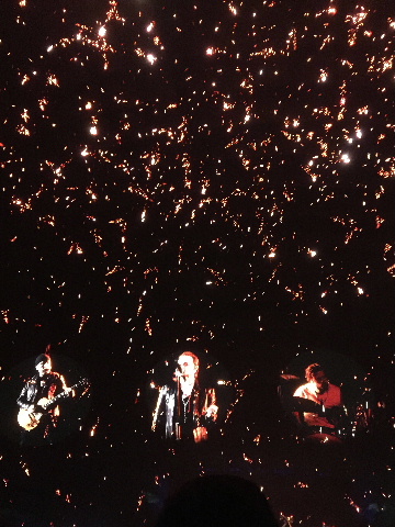 Projected circular images of U2 band members against richly decorated digital sky