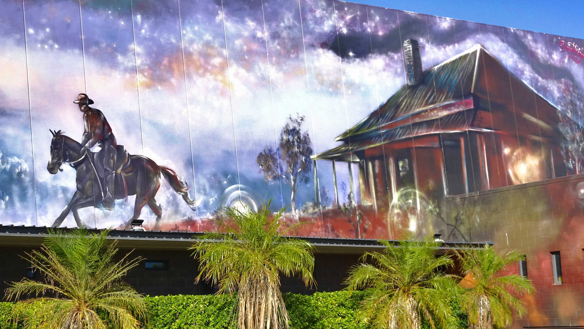 Mural depicting stockman on horse fleeing shanty pub surrounded by Min Min lights