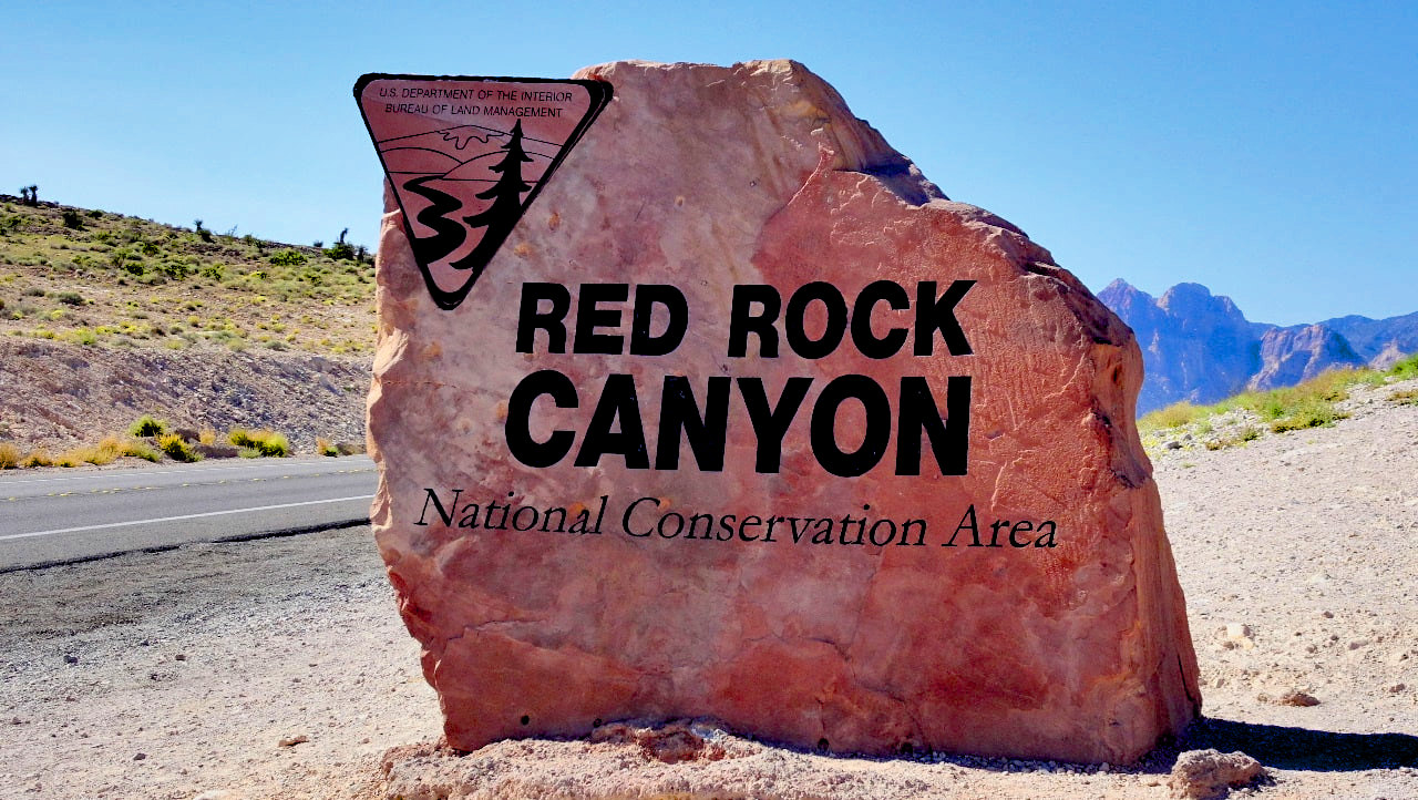 Large rock by side of highway welcoming visitors to Red Rock Canyon, Nevada